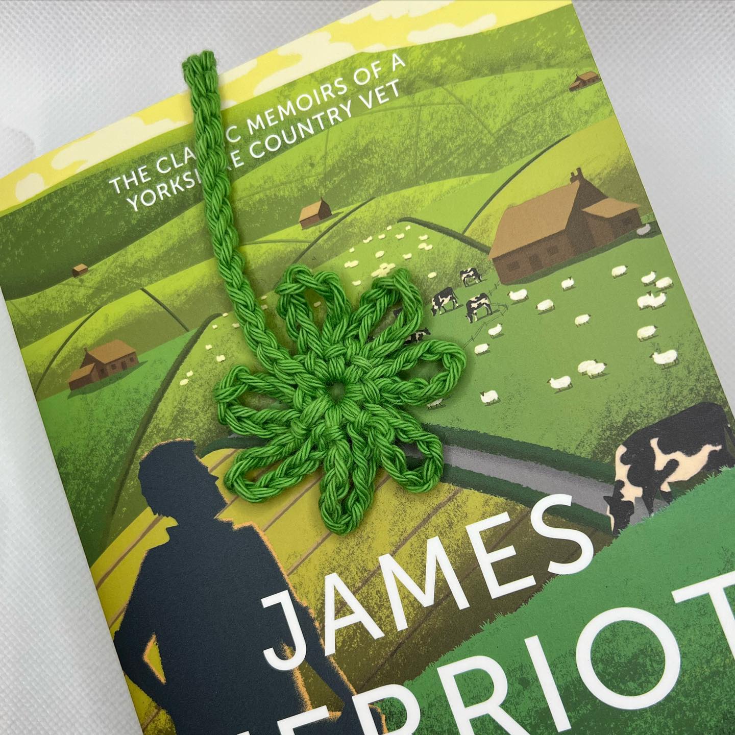 Crochet simple daisy bookmark resting on all creatures great and small by james herriot